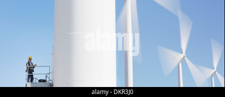 Worker standing on wind turbine in rural landscape Stock Photo