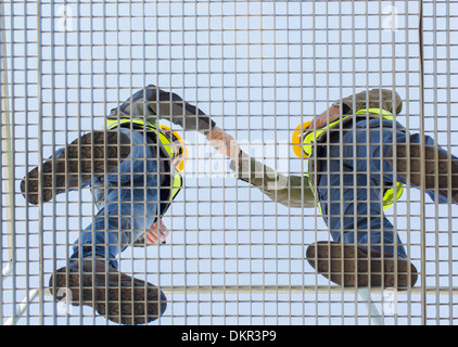 Workers shaking hands on grating Stock Photo