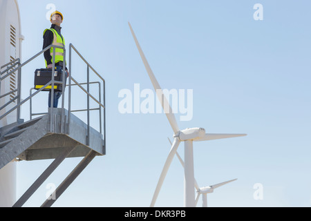 Worker standing on wind turbine in rural landscape Stock Photo