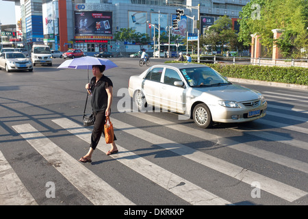 Women walking with umbrella to shade from sun on pedestrian crossing in Shanghai, China Stock Photo