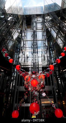Red Christmas decorations in front of the elevator  lift at the entrance to One New Change shopping mall in Central London UK   KATHY DEWITT Stock Photo