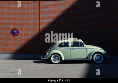 A classic Volkswagen Beetle is parked next to a No Parking sign. Stock Photo