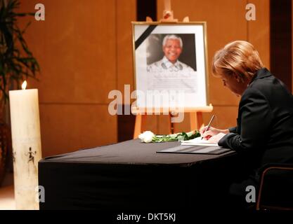 Berlin, Germany. 09th Dec, 2013. German Chancellor Angela Merkel writes her condolences in a book for late former South African President Nelson Mandela at South Africa's embassy in Berlin, Germany, 09 December 2013. The former South African president and anti-Apartheid icon died after a long illness 05 December at the age of 95. He will be buried at his ancestral home in Qunu on 15 December 2013. Photo: FABRIZIO BENSCH/dp/dpa/Alamy Live News Stock Photo