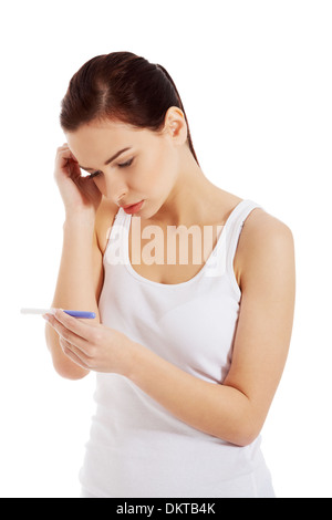 Sad, worried woman with pregnancy test. Isolated on white.  Stock Photo
