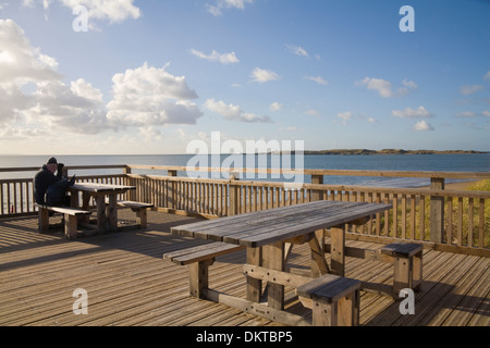 Newborough Anglesey North Wales UK Elderly male walker sitting at newly built picnic tables on disabled friendly platform Stock Photo