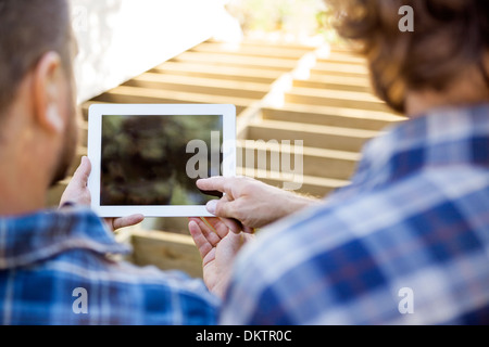 Worker Pointing At Digital Tablet While Coworker Holding It Stock Photo