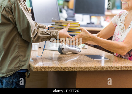 Boy Giving Books To Librarian At Library Counter Stock Photo