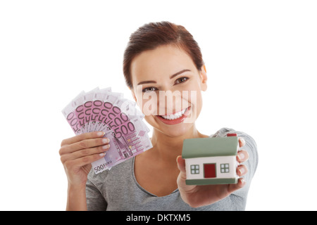 Beautiful young, casual woman holding money and house. Isolated on white. Stock Photo