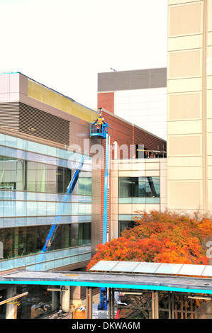 Construction worker in cherry picker works on side of building. Stock Photo