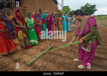 A woman gives agricultural training using a row scoring rake in Bihar State, India Stock Photo