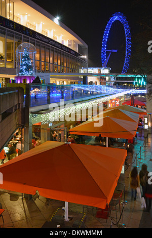 Dark evening view winter lights & Christmas decorations at the South bank Centre Royal Festival Hall with illuminated London Eye beyond England UK Stock Photo