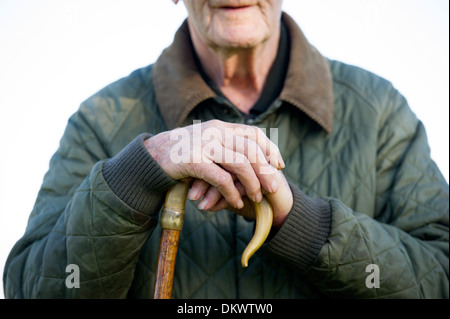 A farmer rests his hands on a walking stick while herding sheep. Stock Photo