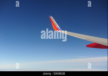 Southwest Airlines wing with winglet on the wing of Boeing 737-700 jet aircraft in flight over clouds Stock Photo