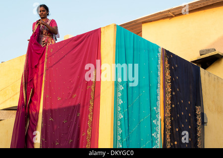 Indian woman hanging saris out to dry outside her rural indian village house. Andhra Pradesh, India Stock Photo