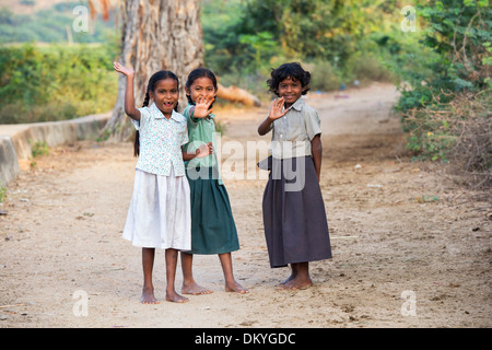 Happy young rural Indian village girls standing on a track waving and smiling. Andhra Pradesh, India Stock Photo
