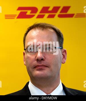 Schkeuditz, Germany. 10th Dec, 2013. Chairman of the board of DHL Hub Leipzig GmbH, Robert Viegers, stands in front of a poster with the company logo at the DHL freight hub at the airport Halle/Leipzig in Schkeuditz, Germany, 10 December 2013. DHL, a subsidiary of Post AG, announced their plans to expand the freight hub Leipzig/Halle the same day. Photo: PETER ENDIG/dpa/Alamy Live News Stock Photo