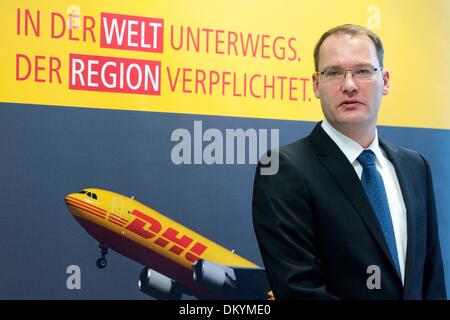 Schkeuditz, Germany. 10th Dec, 2013. Chairman of the board of DHL Hub Leipzig GmbH, Robert Viegers, stands in front of a poster with the company logo at the DHL freight hub at the airport Halle/Leipzig in Schkeuditz, Germany, 10 December 2013. DHL, a subsidiary of Post AG, announced their plans to expand the freight hub Leipzig/Halle the same day. Photo: PETER ENDIG/dpa/Alamy Live News Stock Photo