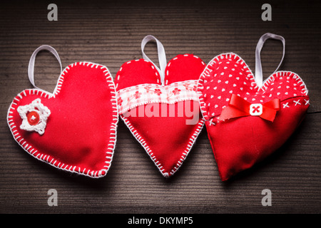 Sewed handmade red hearts on wooden background Stock Photo