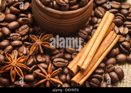 Spilled coffee beans in clay handmade cup with cinnamon and anise Stock Photo