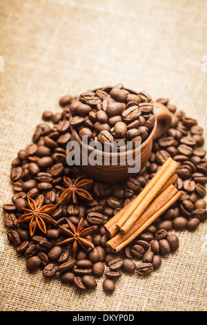 Spilled coffee beans in clay handmade cup with cinnamon and anise Stock Photo