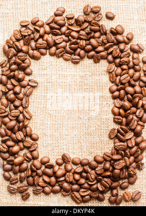 Spilled coffee beans frame over burlap textile Stock Photo