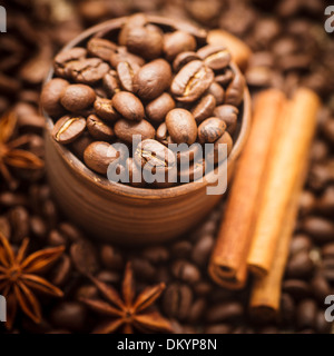 Spilled coffee beans in clay handmade cup with cinnamon and anise Stock Photo