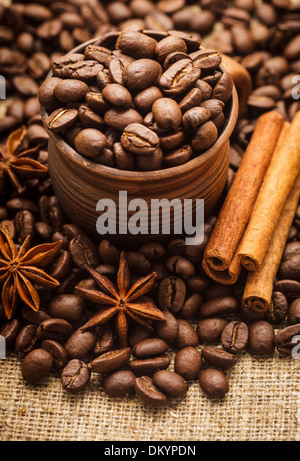 Spilled coffee beans in clay handmade cup with cinnamon and anise Stock Photo