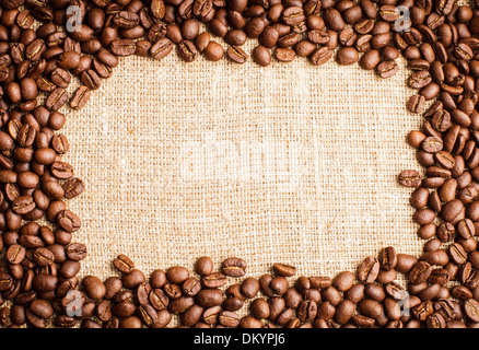 Spilled coffee beans frame over burlap textile Stock Photo
