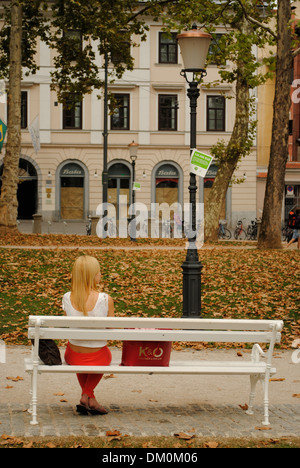 Girl sitting on a bench in a park. Ljubljana, Slovenia Stock Photo