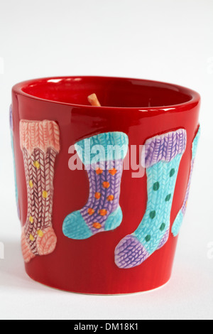 Festive candle in ceramic holder decorated with stockings on isolated on white background Stock Photo