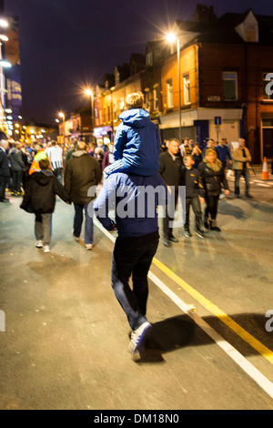 Boy sitting on a man's shoulders on their way to a midweek football match at Everton FC, Goodison Park, Liverpool, UK Stock Photo