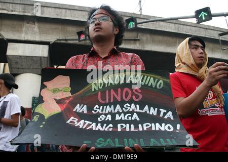 Manila, Philippines. 10th Dec, 2013. A protester holding a poster in Mendiola, Manila comparing President Aquino III to a typhoon that destroyed the Filipino youth. -- Protesters commemorated the International Human Rights Day with a march to Mendiola, Manila bringing effigies of President Aquino III. They dubbed Aquino as the ''impunity king'' for alleged human rights violations since he started his term.Photo: J Gerard Seguia/NurPhoto Credit:  J Gerard Seguia/NurPhoto/ZUMAPRESS.com/Alamy Live News Stock Photo