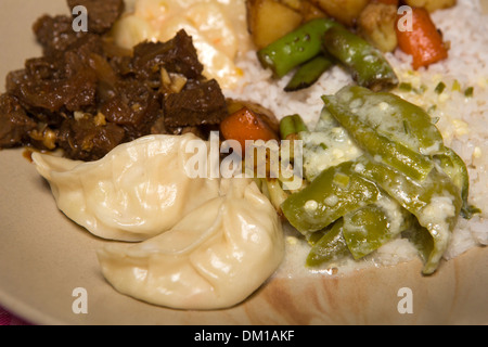 Bhutan, Bhutanese food, plate of ema datse, steamed momos, pork and fried vegetables Stock Photo