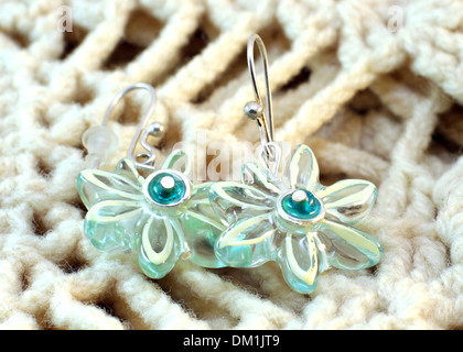 Transparent handmade earrings on the knitted background Stock Photo