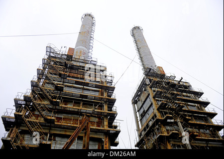 Rusty thermal power plant chimneys with overcast sky in background Stock Photo