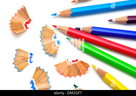 some colored pencils of different colors and pencil shavings on a white background Stock Photo