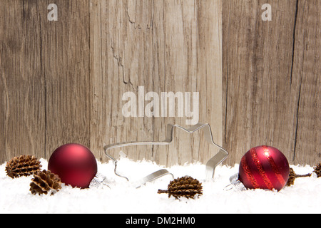 christmas decoration with wooden background, snow, christmas baubles red, shooting star, and pine cones Stock Photo