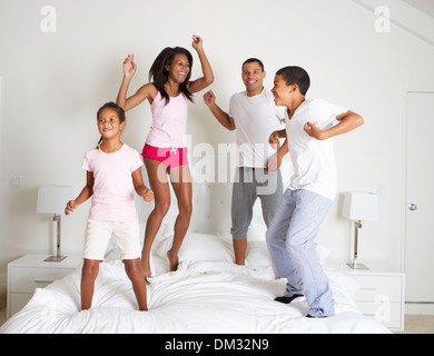 Family Jumping On Bed Together Stock Photo