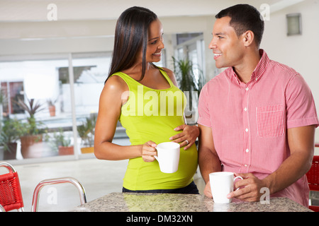 Pregnant Woman And Husband Having Breakfast In Kitchen Stock Photo
