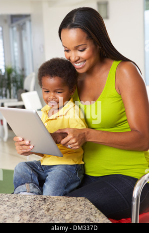 Mother And Son Using Digital Tablet In Kitchen Together Stock Photo