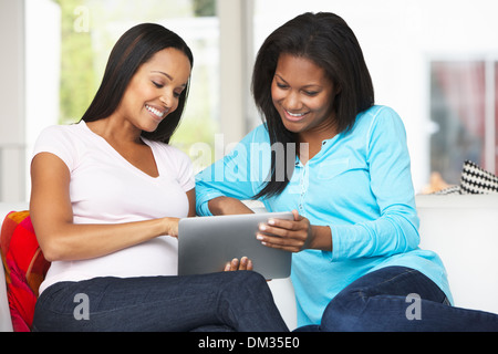 Two Women Sitting On Sofa With Tablet Computer Stock Photo