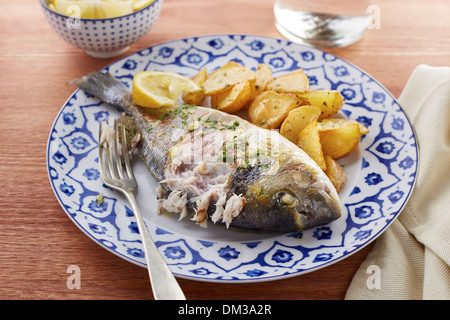 Fried gilt head bream with potatoes in a restaurant table Stock Photo