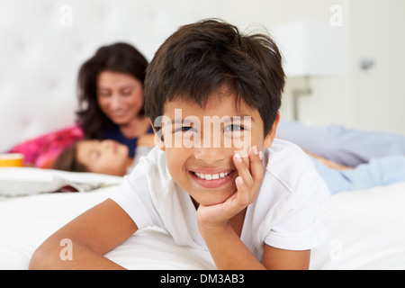 Mother And Children Relaxing In Bed Wearing Pajamas Stock Photo