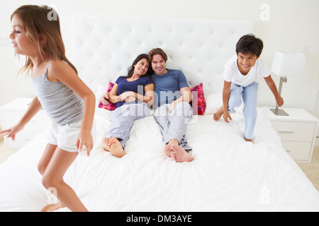 Children Jumping On Parents Bed Wearing Pajamas Stock Photo