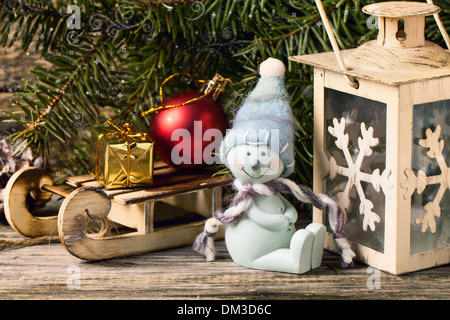 Christmas lantern with snowman and christmas tree on vintage wooden background Stock Photo