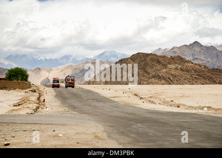Ladakh, India - 13 July 2009: local transport on a remote road surrounded by high mountains. Dramatic clouds and sky. Stock Photo