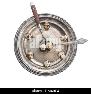 Clock made of quail eggs on silver plate with fork and spoon, isolated on white background Stock Photo