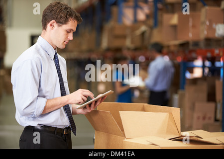 Manager In Warehouse Checking Boxes Using Digital Tablet Stock Photo