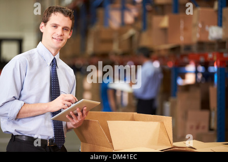 Manager In Warehouse Checking Boxes Using Digital Tablet Stock Photo
