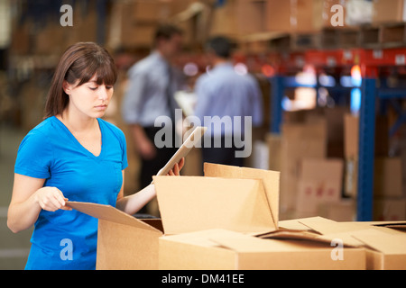 Worker In Warehouse Checking Boxes Using Digital Tablet Stock Photo